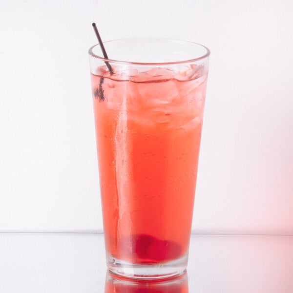 A Libbey customizable mixing glass filled with red liquid and a straw.