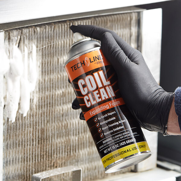 A hand uses Noble Chemical Tech Line Expanding Foam Aerosol Coil Cleaner on a metal surface.