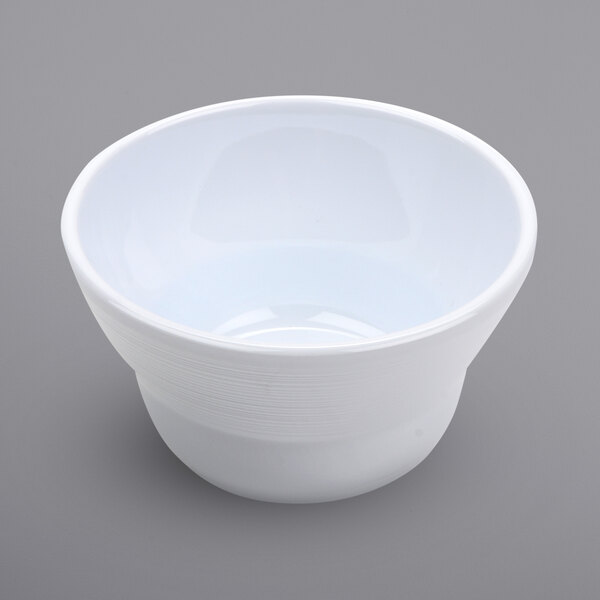 A white Minski melamine bowl with a textured rim on a gray surface.
