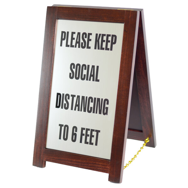 A wooden social distancing sign on a chain.
