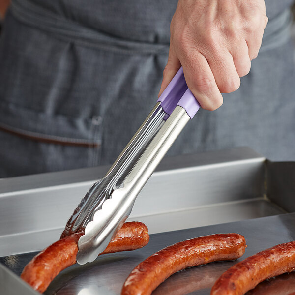 San Jamar Saf-T-Zone stainless steel tongs with a purple allergen-free handle being used to put meat on a piece of sausage.