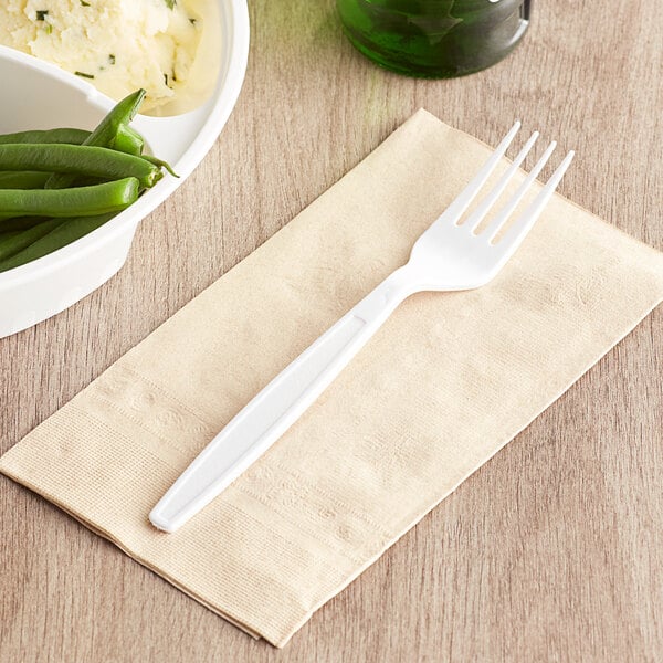 A Visions white plastic fork on a napkin next to a bowl of green beans.
