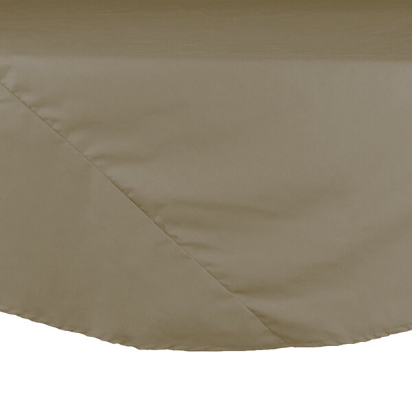A close-up of a beige Intedge hemmed round table cloth on a table.
