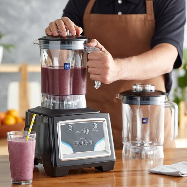 A person in an apron using an AvaMix commercial blender to make a smoothie.