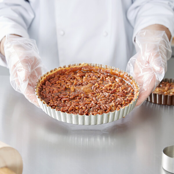 A hand holding a round tart with a removable bottom.