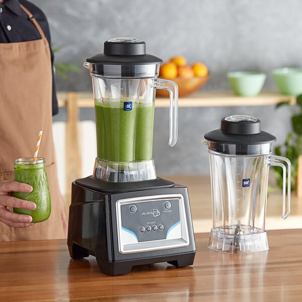 A person using an AvaMix commercial blender to make a green smoothie.