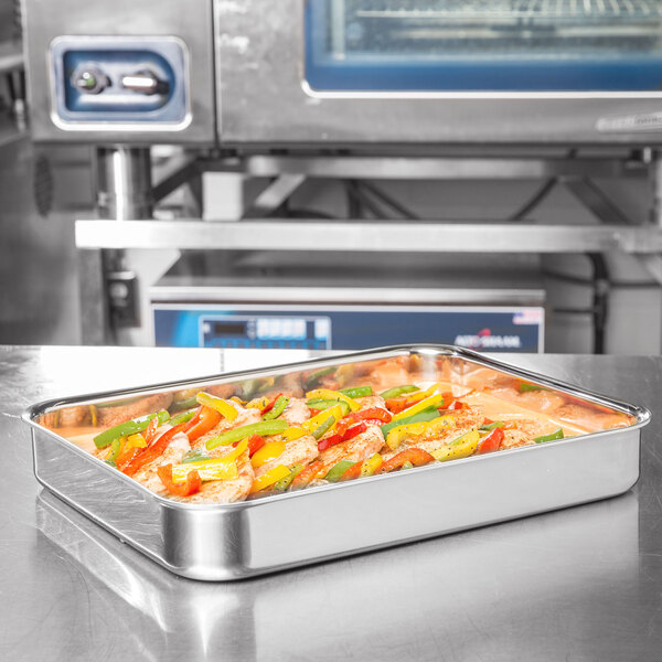 A Vollrath stainless steel roasting pan filled with food on a counter.