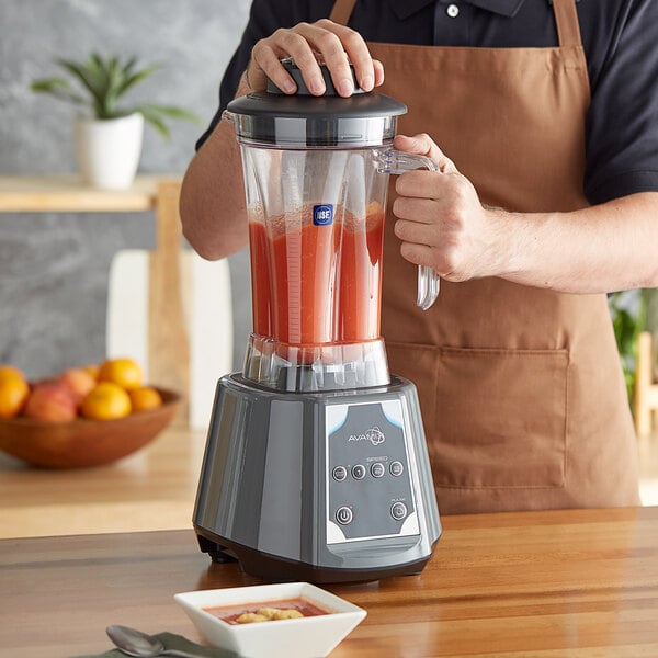 A person in an apron using an AvaMix commercial blender to make a smoothie.