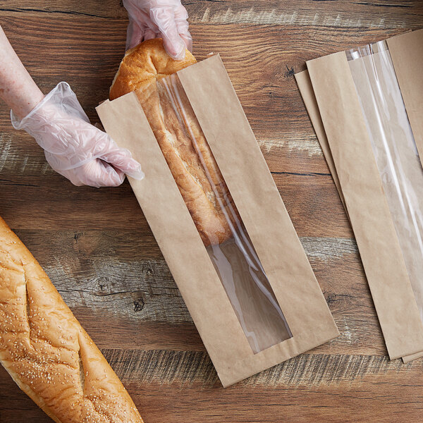 A person in gloves holding a loaf of bread in a Durable Packaging paper bag with a window.