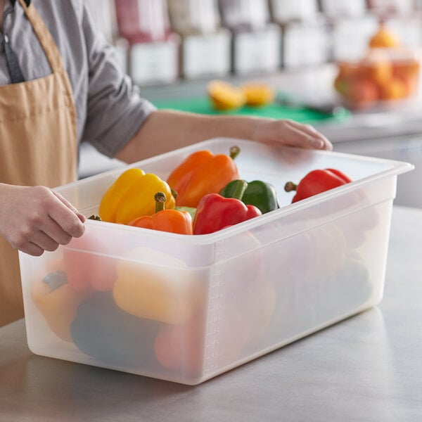 A woman holding a Cambro translucent plastic container full of peppers.
