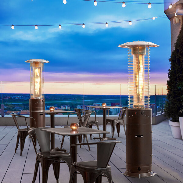 A Backyard Pro bronze portable patio heater on a deck with tables and chairs.
