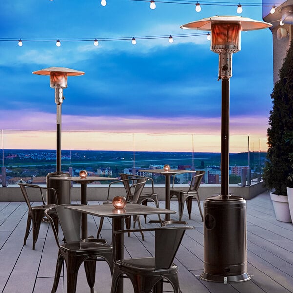 A black Backyard Pro portable patio heater on an outdoor patio with tables and chairs.