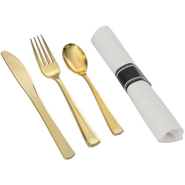 A white paper napkin with a pre-rolled gold plastic flatware set including a fork, knife, and spoon.