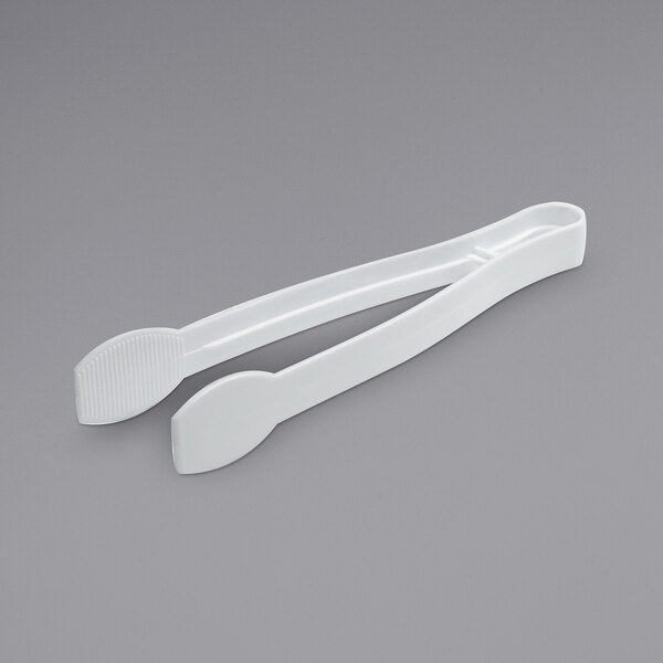 Two white Fineline ridged plastic tongs on a gray surface.
