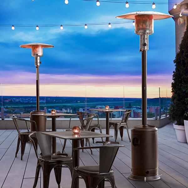 A Backyard Pro bronze portable patio heater on a commercial patio with tables and chairs.
