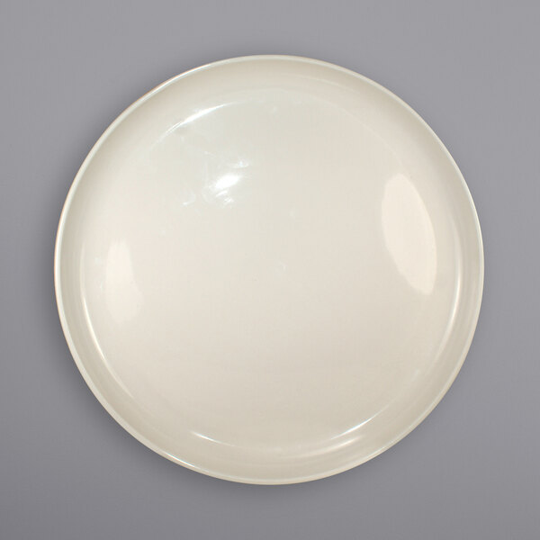 An ivory stoneware pizza plate with a small rim on a gray surface.