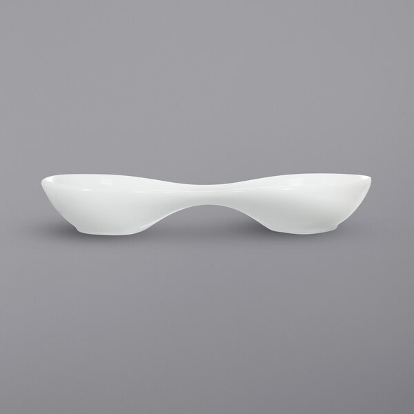 A white International Tableware porcelain bowl with 2 round wells and curved edges.