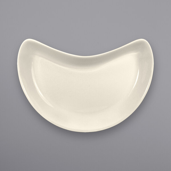 An International Tableware ivory stoneware crescent dish with a curved edge on a white background.
