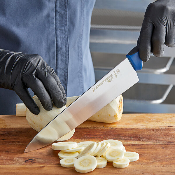 A person in black gloves cutting vegetables in a professional kitchen with a Dexter-Russell 36006C chef knife.