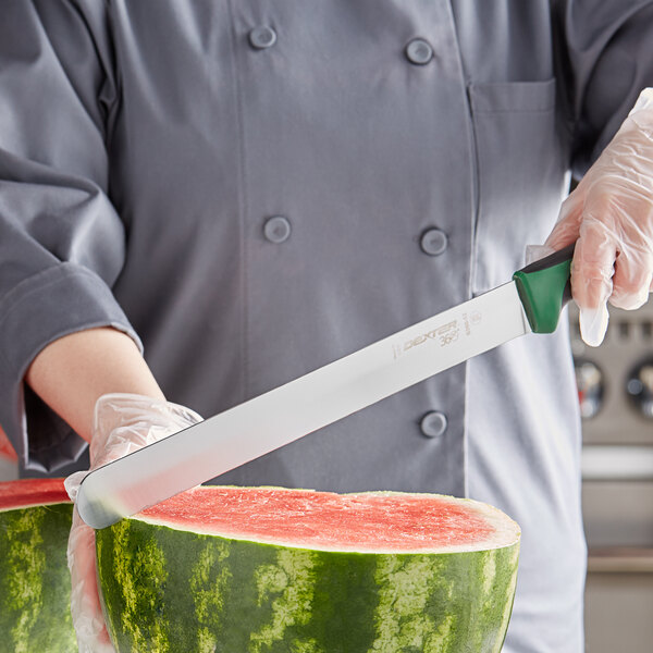 A person using a Dexter-Russell 12" slicing knife to cut a watermelon.