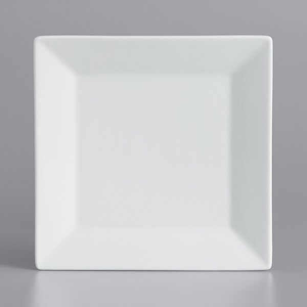 A white square International Tableware porcelain plate with a wide rim on a gray surface.