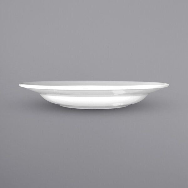 A close up of a white International Tableware porcelain pasta bowl with a wide rim.