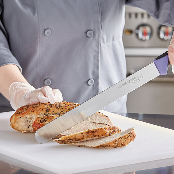 A chef using a Dexter-Russell slicing knife to cut meat on a counter.