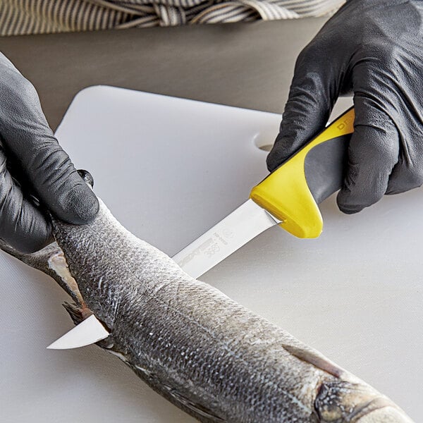 A person in black gloves using a Dexter-Russell yellow-handled narrow boning knife to cut fish on a cutting board.