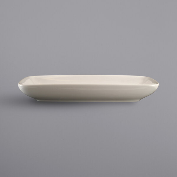 An International Tableware rectangular ivory stoneware relish dish on a gray surface.