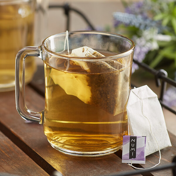 A glass mug of Numi Organic Sweet Slumber tea with a tea bag on the table.