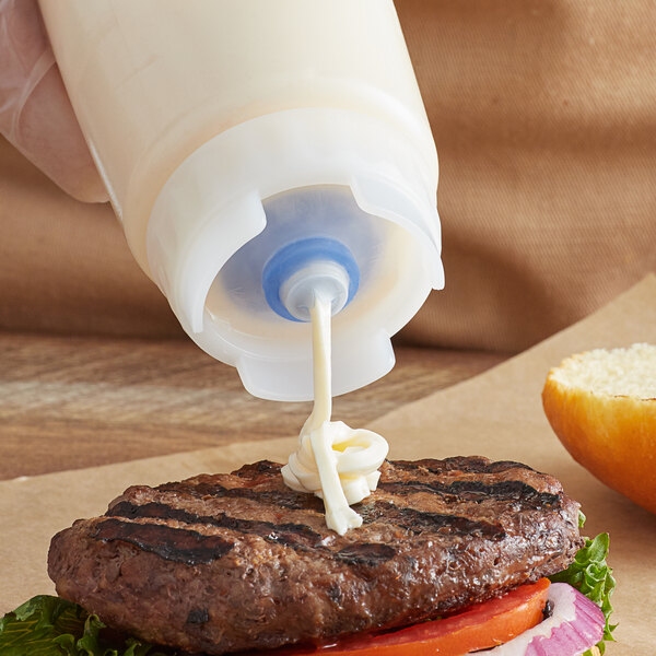 A person using a FIFO Innovations squeeze bottle valve to pour mayo on a burger.