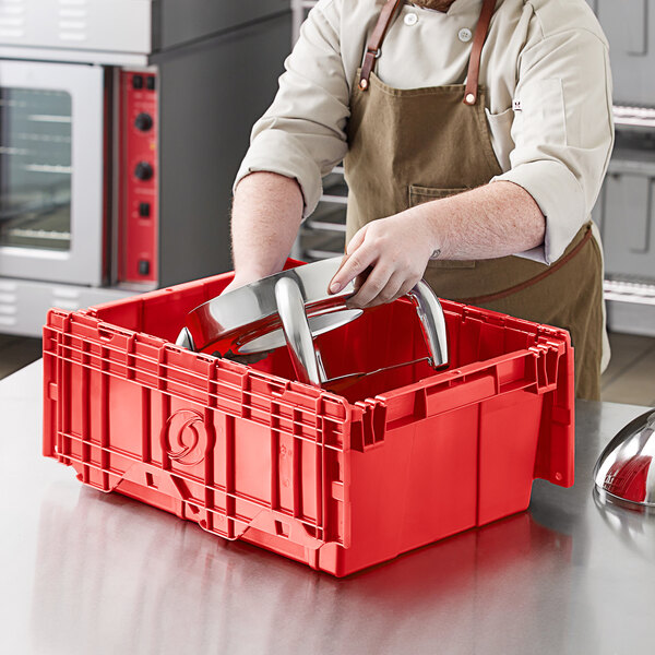 A man in an apron using a red Orbis plastic tote box to hold metal objects.