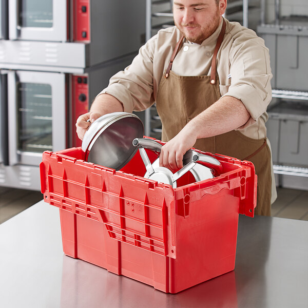 A man in an apron putting a pot into a red plastic container.