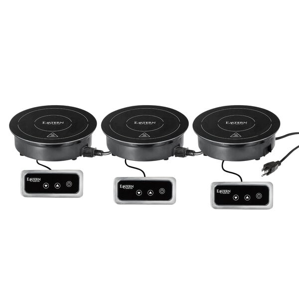 A row of three black Eastern Tabletop Daisy Chain induction ranges with different controls.