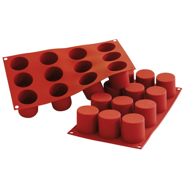 A red Silikomart silicone baking mold with twelve cylindrical cavities.
