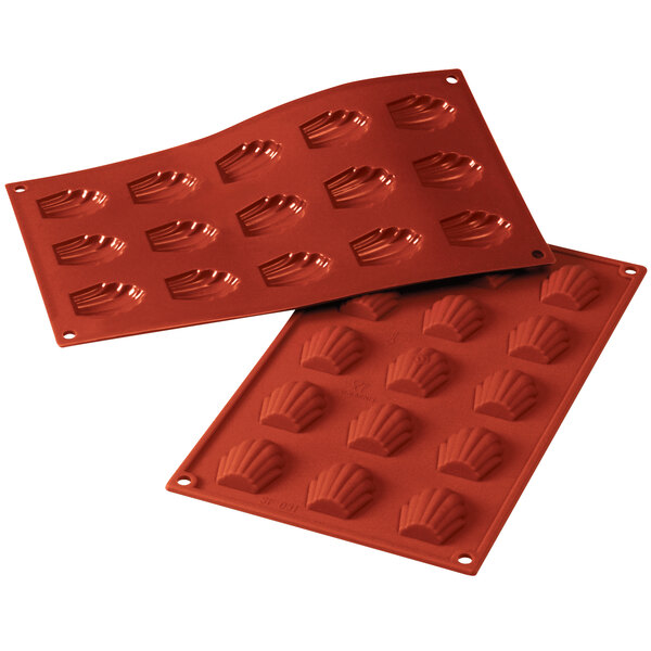 A close-up of a red Silikomart silicone baking mold with 15 madeleine cavities.