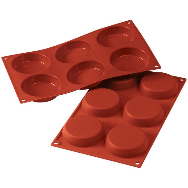 A red silicone baking tray with six flan-shaped circles.