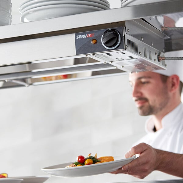 A chef using a ServIt double strip warmer to heat a plate of food.