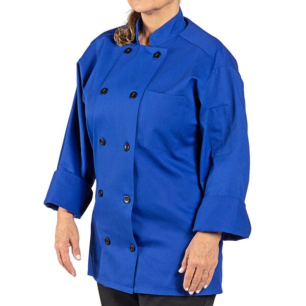 A woman wearing a royal blue Uncommon Chef long sleeve chef coat.