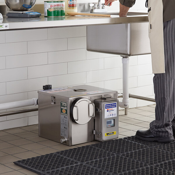 A man in a professional kitchen using a Grease Guardian CG-4 Combi Guardian.