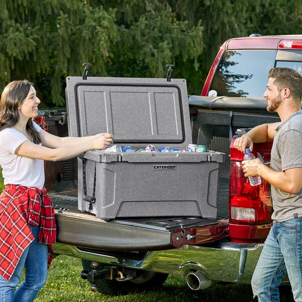 A man and woman loading CaterGator coolers into a truck.