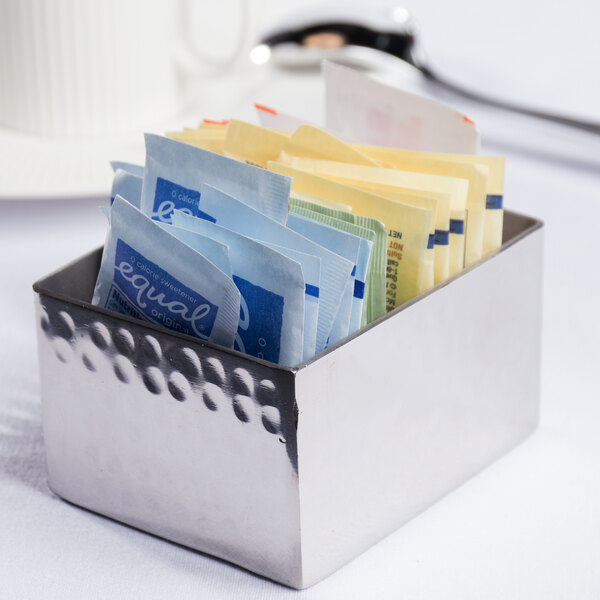 An American Metalcraft stainless steel rectangular sugar caddy with packets of sugar inside.