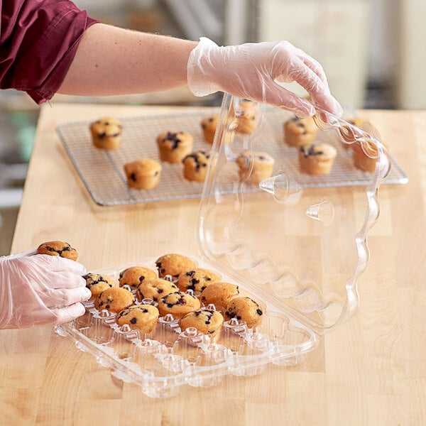 A person wearing gloves holding a clear plastic InnoPak container with mini muffins.