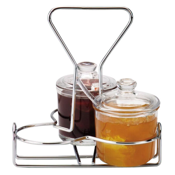 A Vollrath wire rack holding two glass jars filled with brown liquid.