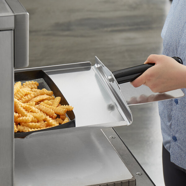 A person holding a Merrychef paddle peel with fries in a rapid cook oven.