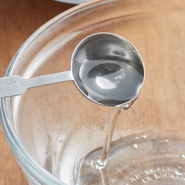 A spoon pouring Golden Barrel High Fructose Corn Syrup into a glass bowl.