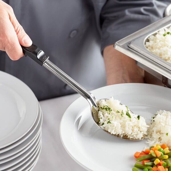 A person using a Vollrath stainless steel spoon to serve rice and vegetables.