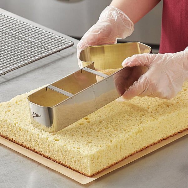 A person in gloves using an Ateco stainless steel number 1 cutter to cut a cake.