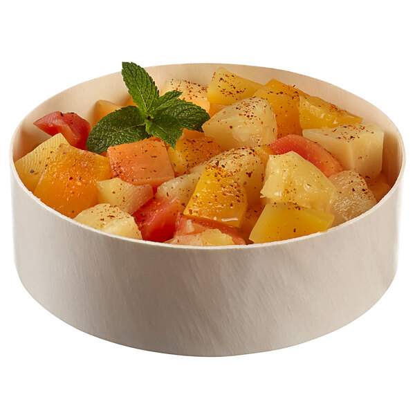 A Solia laminated wooden bowl filled with fruit salad on a table.