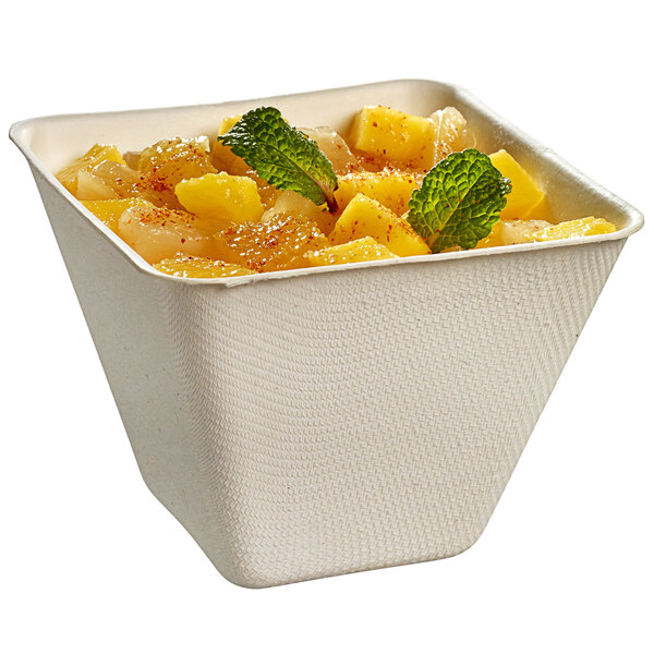 A Solia white sugarcane bowl filled with pineapple and mint leaves.